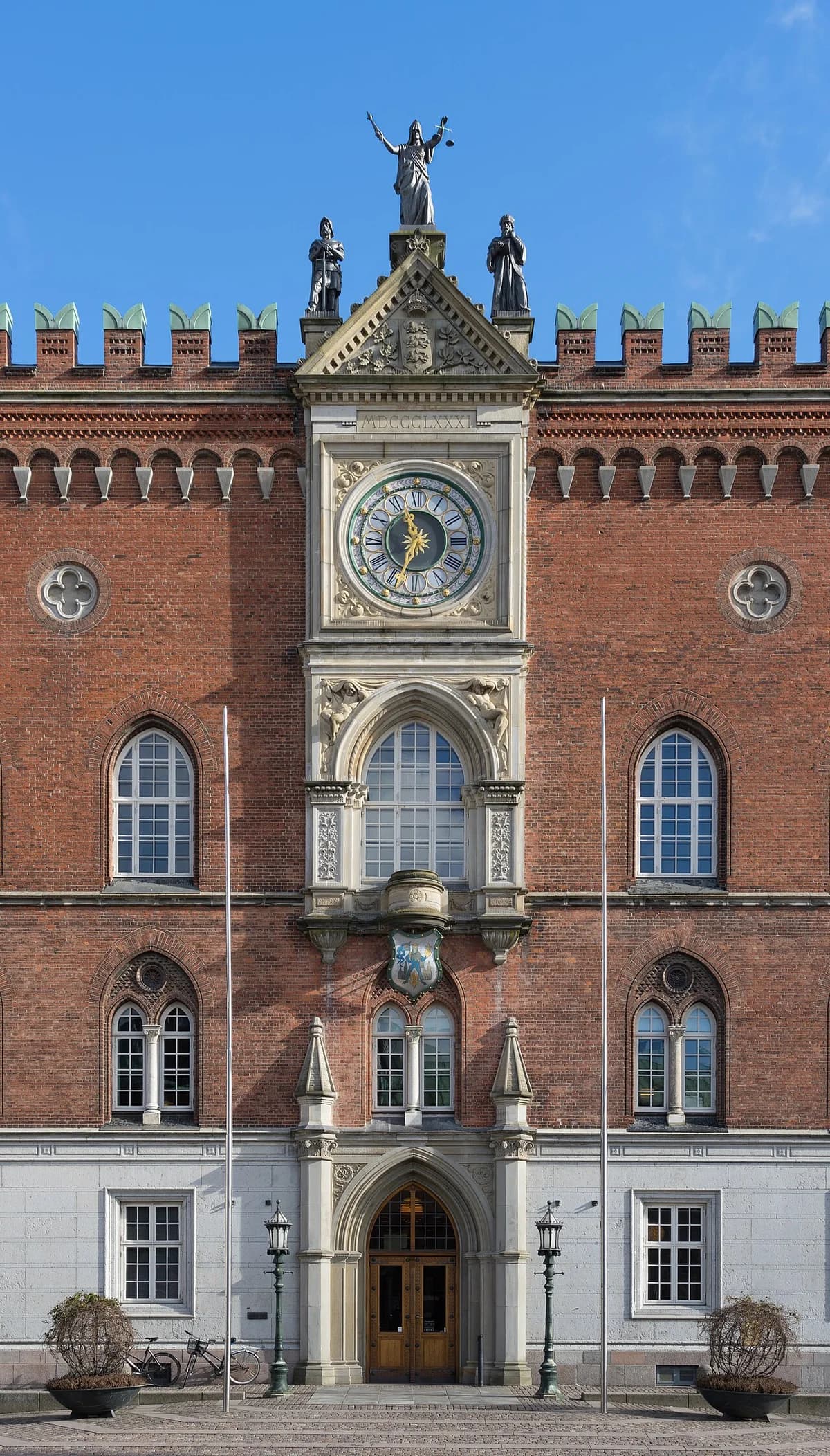 Facade of Odense City Hall with a clock, statues, and arched windows.
