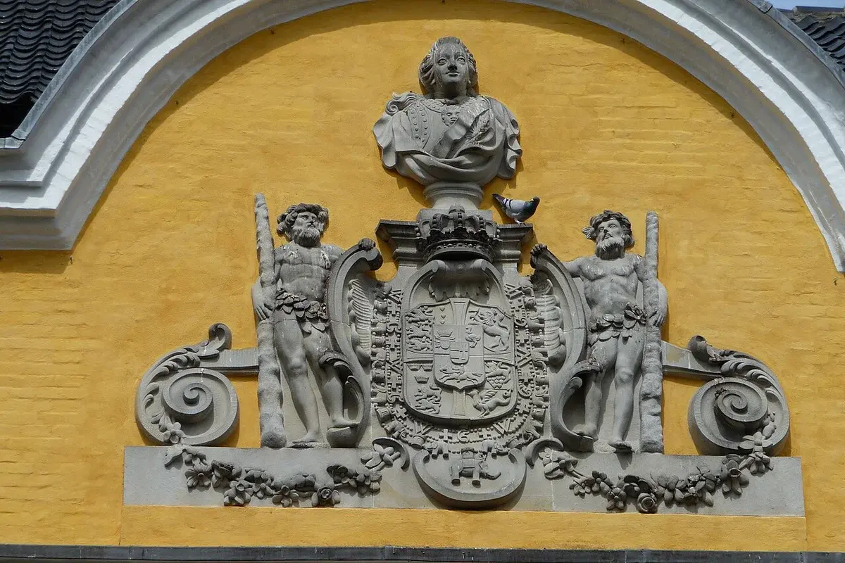 Ornate stone decorations on a yellow building facade in Aalborg, Denmark.