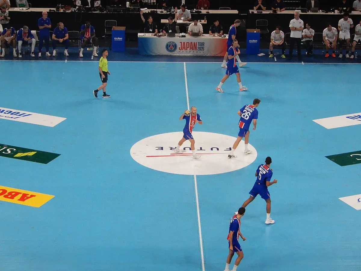 Handball match between Paris Saint-Germain and a Japanese team on an indoor court.