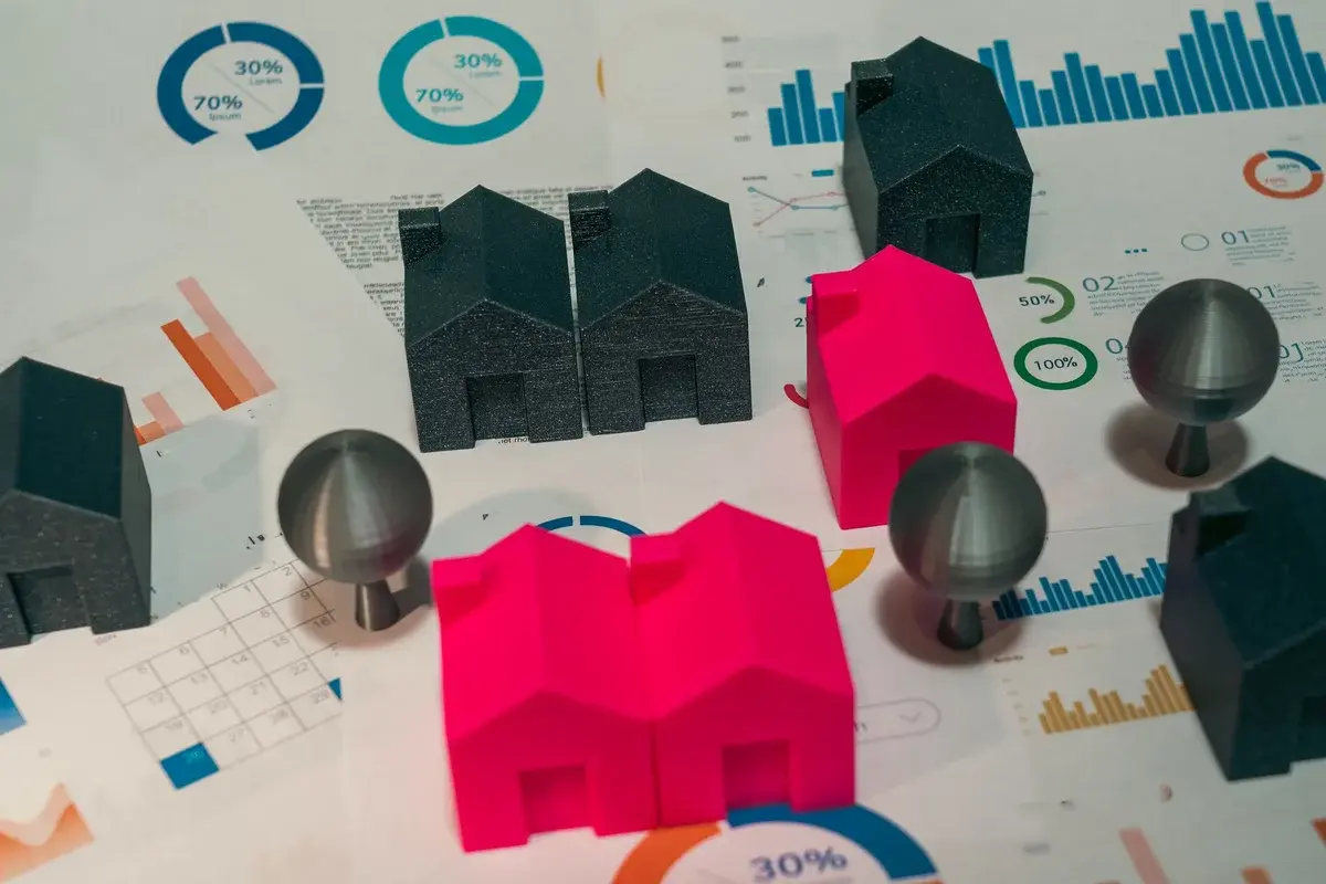 Miniature house models and trees on papers with graphs and charts