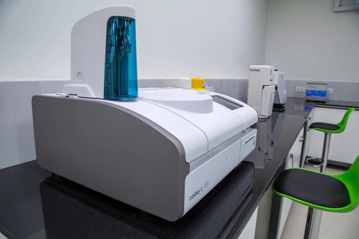 A large modern lab machine sits on a black countertop in a clean laboratory.