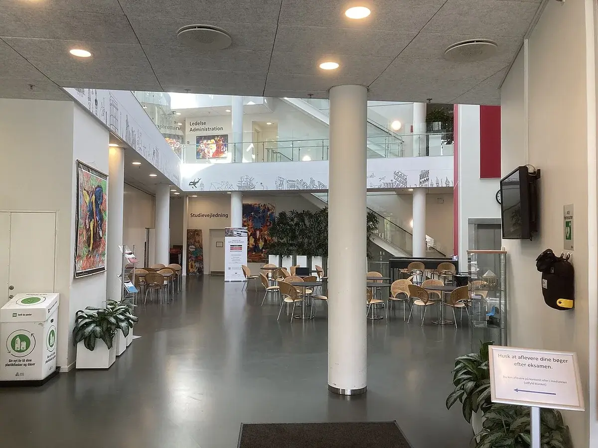 Interior lobby of a school building with seating and stairs.