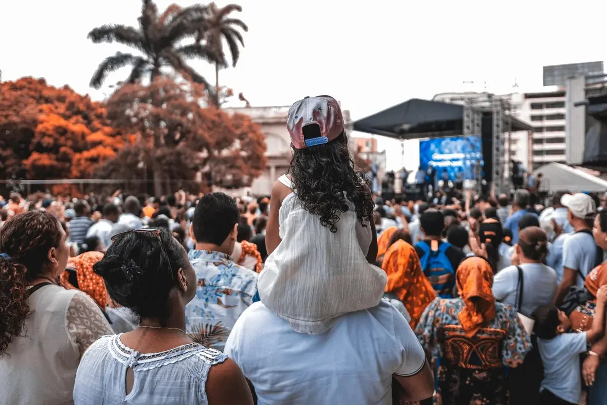 A crowd gathered outdoors to watch a music stage at a festival.