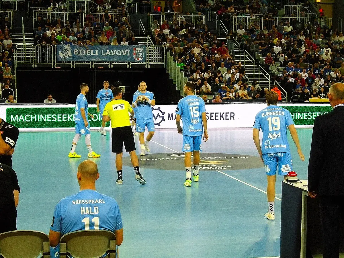 Aalborg Handball players on the court in Zagreb Arena during a match.